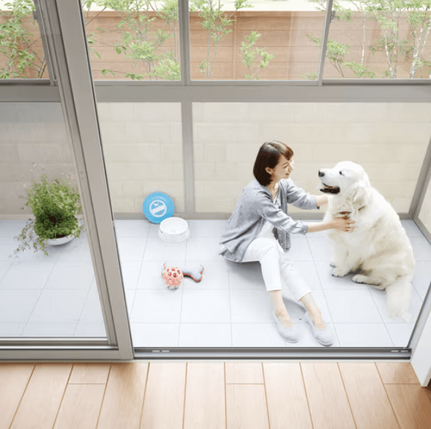 リクシルのサンルームサニージュでくつろぐ大人と白い犬